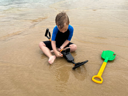 a boy looking for treasures on the beach, with a metal detectorの写真素材