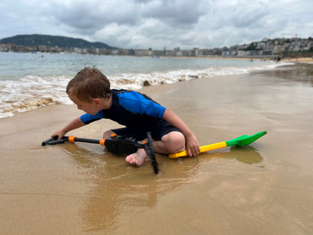 a boy looking for treasures on the beach, with a metal detectorの写真素材