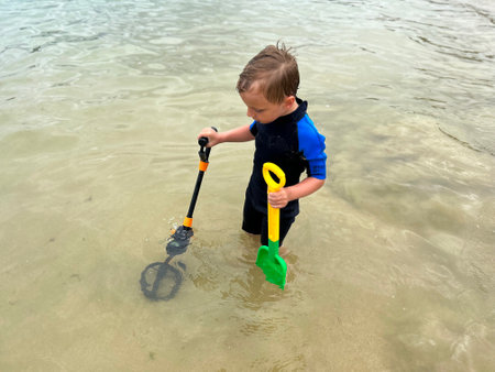 a boy looking for treasures on the beach, with a metal detectorの写真素材
