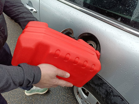 a man pours fuel into a gas tank from a canisterの写真素材