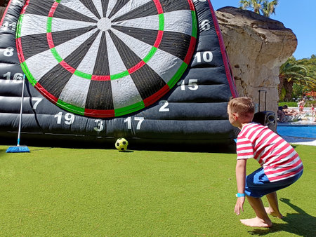 a blond boy, on summer vacation, plays hitting a huge inflatable target with a ballの写真素材