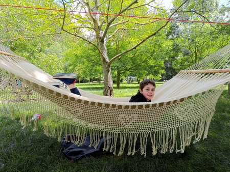 happy child lying in a hanging hammock, outdoorsの写真素材
