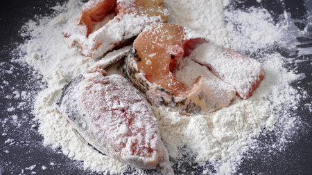 Fish cut into pieces, sprinkled with flour, on a black backgroundの写真素材