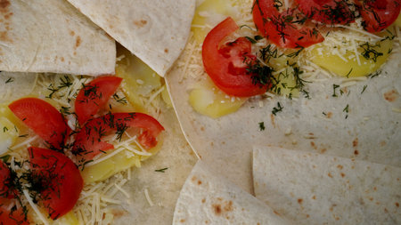 Vegetable kebab in the process of cooking, flatbread dough, tomatoes and potatoes, up close