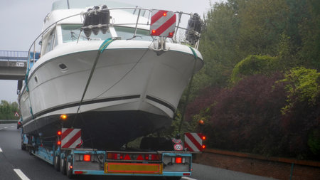 truck loaded with a large yacht, circulates on the highwayの写真素材