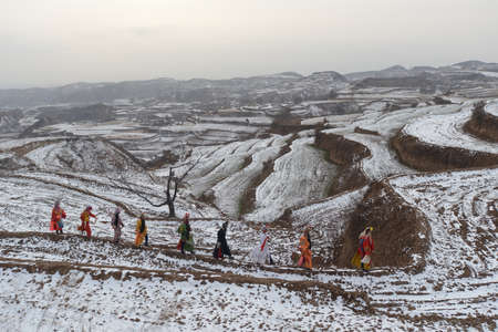 people wearing costume walking through the snow hillのeditorial素材