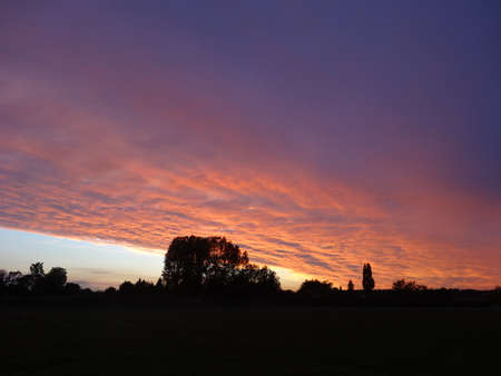 Sunset in the countryside with the silhouettes of trees and a churchの写真素材