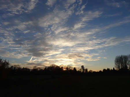 Sunset over the field in the winter. Blue sky with white clouds.の写真素材