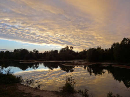 Sunset over the river. Beautiful sky with clouds reflected in the water.の写真素材