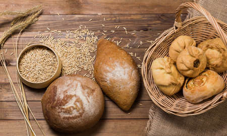 Assortment of bread, ears and grains of wheat on wooden tableの写真素材