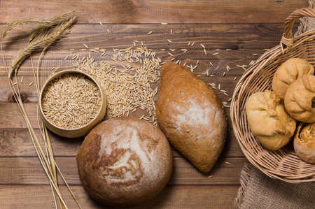 Assortment of bread, ears and grains of wheat on wooden tableの写真素材