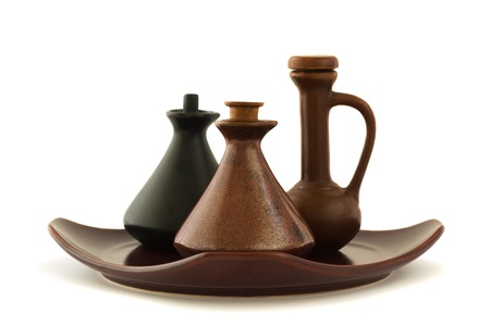 Three massage oil ceramic bottles standing on a brown squaere plate, isolated on whiteの写真素材
