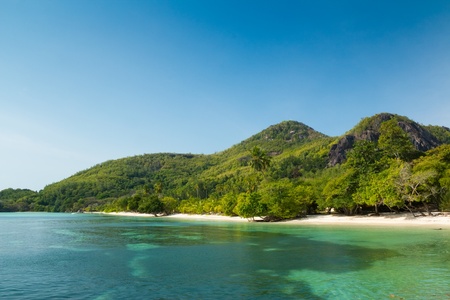 A small turquoise crystal clear tropical beach by mountain in St Anne Island, Seychellesの写真素材