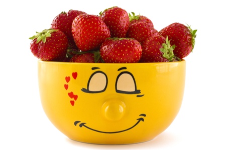 Large yellow cup with a shy face print full of ripe strawberries, isolated on a white background.の写真素材