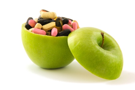 Green apple filed with colourful pills, isolated on white background.の写真素材