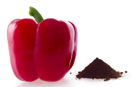Vibrant red bell pepper and a heap of paprika isolated on white backgroundの写真素材
