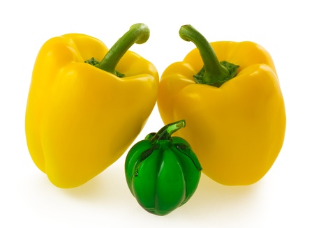 Two yellow bell pepper together with small green glass bell pepper ornament, isolated on white backgroundの写真素材