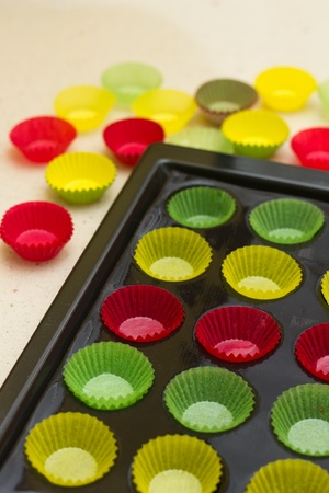 Mini cupcake tin with vibrant colorful cupcake papers ready to be filled with batterの写真素材