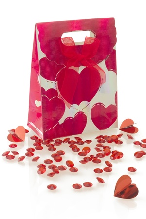 Red gift bag with heart pattern and bow, with a heart shaped decoration, isolated over white background.の写真素材