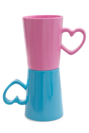 Pink and blue cups with heart element isolated on white background の写真素材