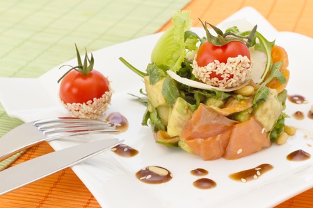 Avocado and salmon salad with small tomato on topの写真素材