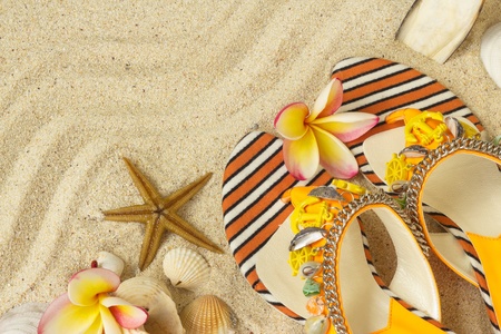 Sandals, seashells, starfish and frangipani on sand の写真素材