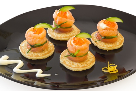 Red salmon roll with cheese, caviar and cucumber on  blini  base, on black plate の写真素材