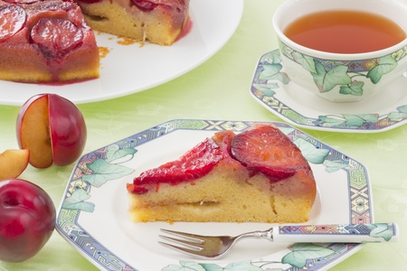 Slice of plum cake on plate, with cup of teaの写真素材