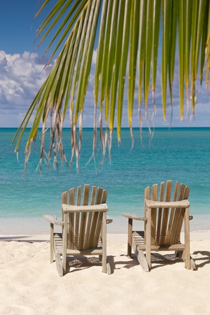 Beach chairs on white sand beach with cloudy blue sky and sunの写真素材
