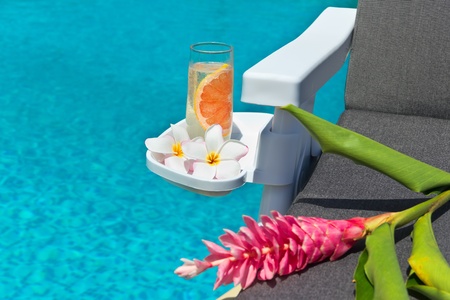 A glass of fresh lemonade, frangipani flowers and torch Ginger flower on resting chair, by Swimming pool  の写真素材