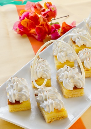 Group of Mini square sponge cakes with merengue topping and chocolate spirally decoration の写真素材