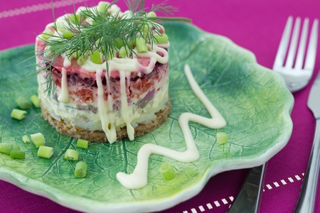 Beetroot salad with carrot, onion, potato, herring,  garnish with mayonnaise, spring onion and dill