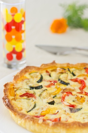 Home made vegetable quiche with colorful glass and orange flower on backgroundの写真素材