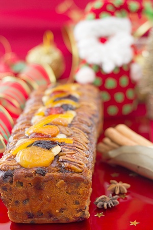 Christmas Fruit-cake with festive decoration, vertical composition, on redの写真素材