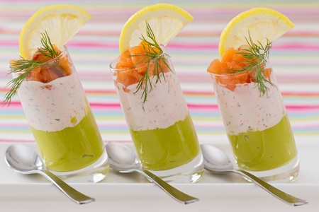 Salmon and avocado mousse garnished with smock salmon, slice of lemon and dill on white plateの写真素材