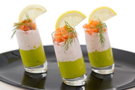 Salmon and avocado mousse garnished with smock salmon, slice of lemon and dill, on black plateの写真素材