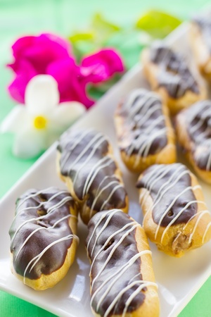 Chocolate Ã©clairs on square white plate, on green backgroundの写真素材