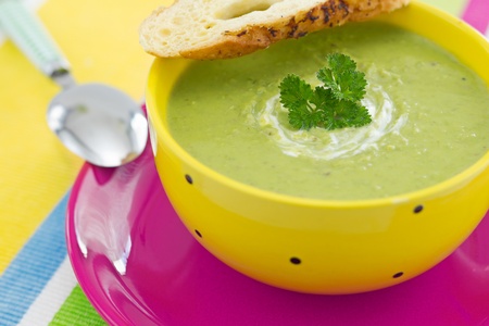 Pea cream soup with parsley and croutons, on pink plateの写真素材
