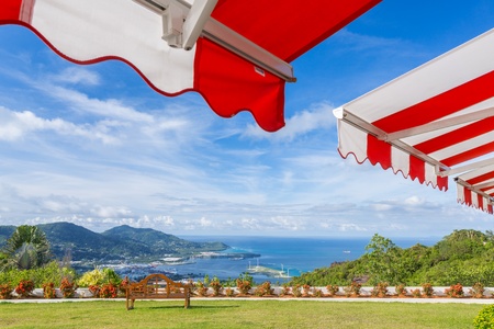 Awning over bright sunny blue sky with bench and sea view の写真素材
