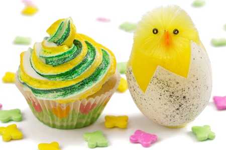 Yellow and green cupcake with toy chick and multicolored decoration, isolated on white background 