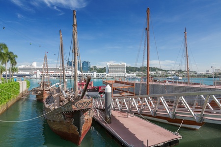 Old fashion boat on foreground and large tourist cruiser on background, Singaporeの写真素材