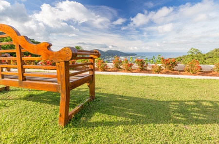 Empty wooden bench with a beautiful view of sea, sky and hillsの写真素材