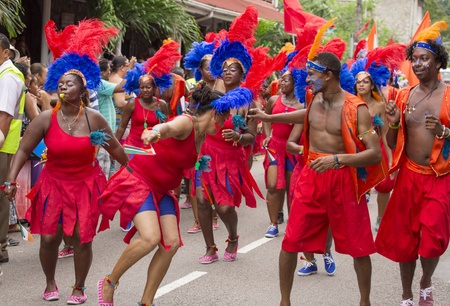 Victoria, Seychelles - February 9, 2013:  Group of Seychelles performers in vibrant red outfit walking on streets of Victoria, on Parade of Seychelles international Carnivalのeditorial素材