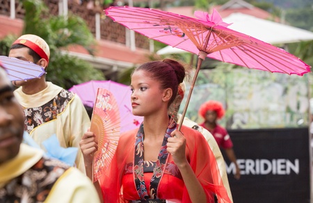 Victoria, Seychelles - February 9, 2013: Young woman in red dress holding pink parasol walking on Parade of Seychelles international Carnivalのeditorial素材