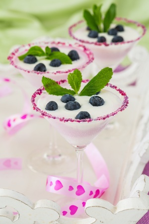 Fresh blueberry yogurt dessert in martini glasses and leafs of mint for decorationの写真素材