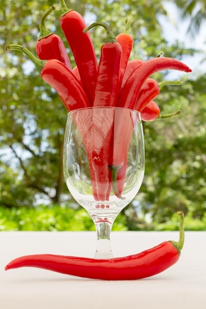 Bunch of fresh red hot  chilli  chilie peppers in a glass jar, with single one by the sideの写真素材