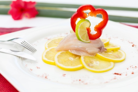 Fish Carpaccio on lemon slices, decorated with bell pepper slice and limeの写真素材