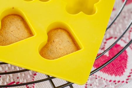 Vanilla  sponge cake hearts in yellow silicone mold, cooling on metal rackの写真素材