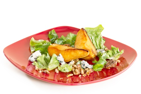 Salad with caramelised pears,walnuts and blue cheese, on red plate, isolated on white backgroundの写真素材