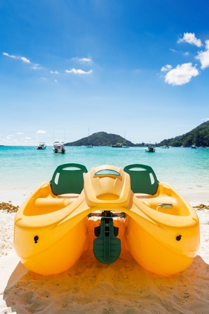Yellow water bicycle  berthed at the beach, with stunning view of ocean and hillsの写真素材